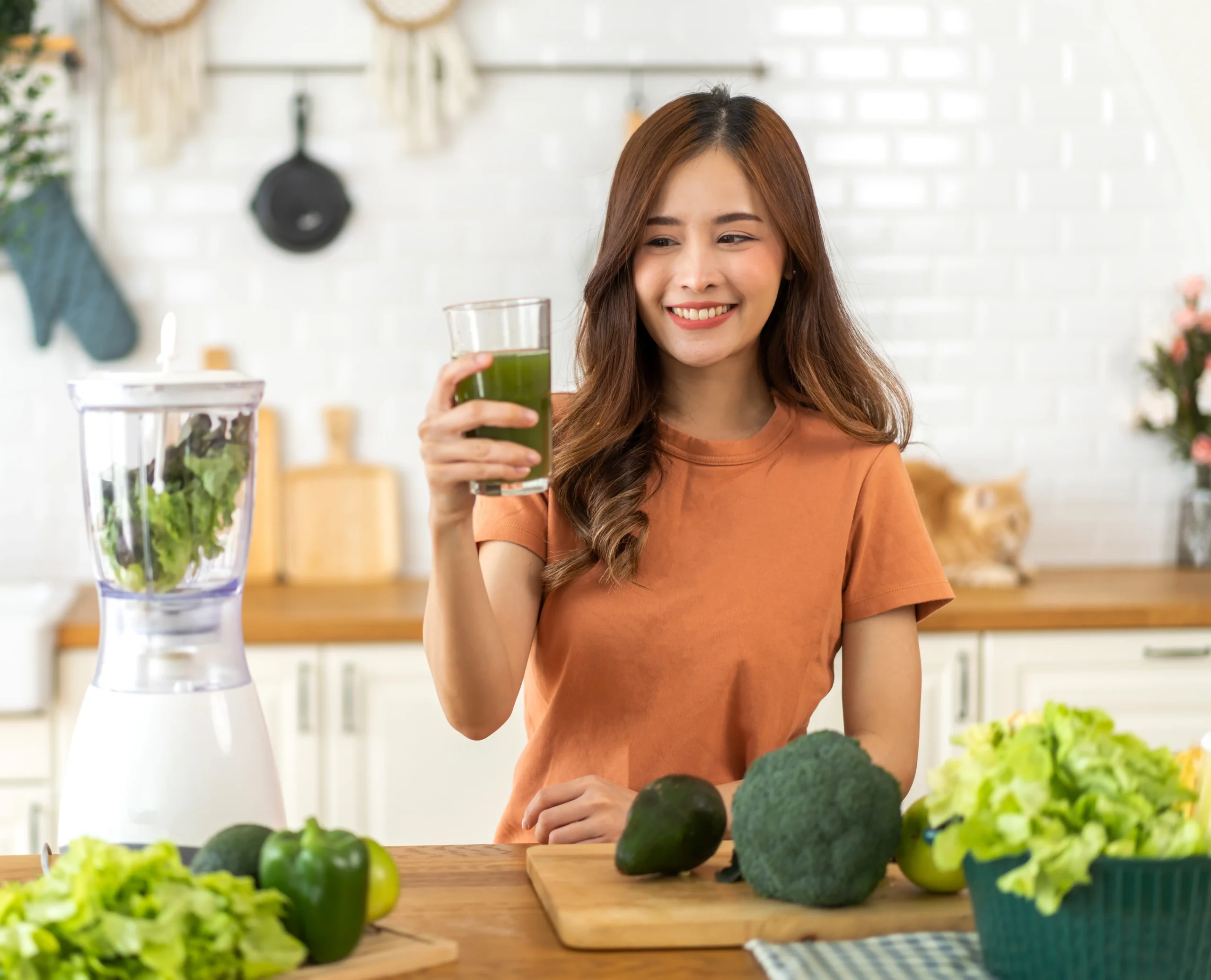 mujer sonriendo mientras toma un vaso de jugo verde